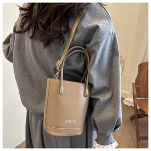Detail of beige bucket bag with silver Fashion logo being worn by a model