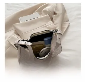 Détail intérieur du sac croissant crème montrant sa capacité de rangement pour maquillage et portefeuille