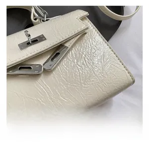 Détail du fermoir argenté et du cuir plissé sur ce sac à main blanc crème