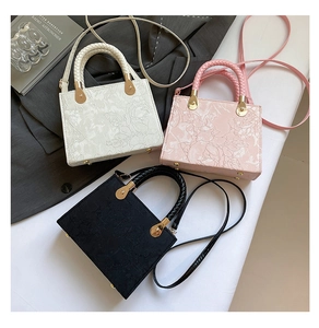 Macro detail of embossed floral fabric texture and golden base studs on minimalist handbag