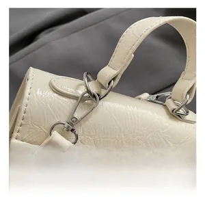 Détail du fermoir rotatif argenté et de la texture plissée sur le sac à main beige
