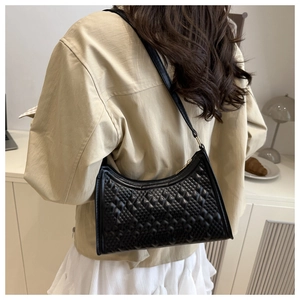 Detail of black quilted shoulder bag featuring matte leather texture and crescent shape