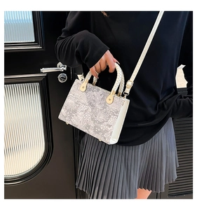 Detail of crossbody bag with floral pattern and white woven handle on a female model