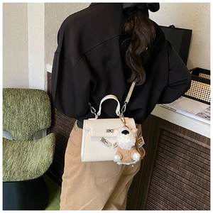 Détail d'un sac à main blanc style Kelly avec un charme de chiot et fermoir rotatif
