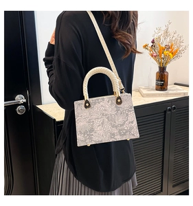 Detail of white lace embossed handbag featuring woven handle and elegant gold hardware