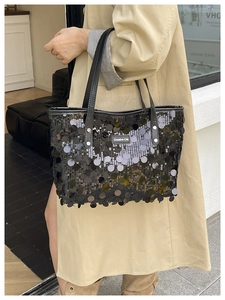 Close-up of black sequined tote bag with Creative Cat label and leather handles