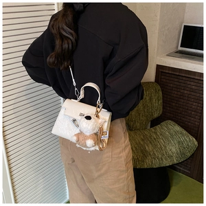 Sac à main en cuir verni blanc avec breloque chien peluche porté en bandoulière