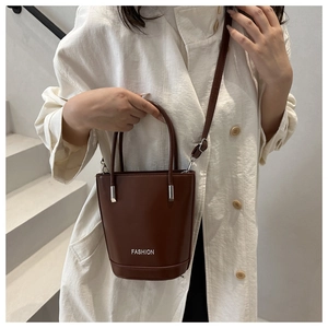 Close-up of a dark brown bucket bag with white fashion text and metallic strap details