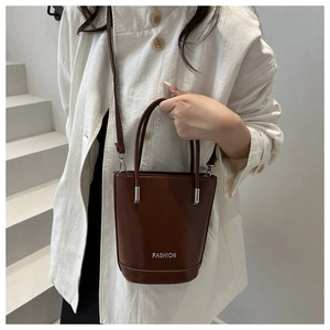 Close-up of brown bucket bag with Fashion lettering and silver metal strap hooks