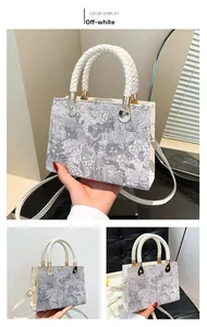 Detail showing jacquard texture, woven handles, and gold hardware on cream white handbag