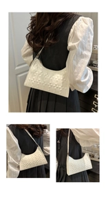 Detailed view of white quilted faux leather croissant bag with gold metal buckle