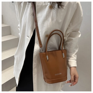Detail of caramel leather bucket bag with silver Fashion logo and adjustable shoulder strap