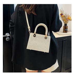 Detail of cream mini tote bag featuring 3D rose floral embossing and gold hardware