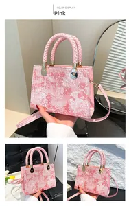 Detailed view of a pink embossed handbag with floral lace pattern and braided leather handle