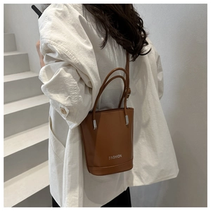 Brown leather bucket bag detail with Fashion metallic logo and shoulder strap