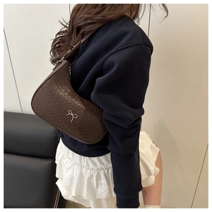 Dettaglio borsa a spalla a mezzaluna con fiocco metallico e trama in pelle intrecciata
