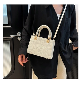 Detailed view of a white embossed crossbody bag with woven handle on a shoulder model