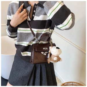 Détail du sac Kelly en cuir verni marron foncé avec fermoir argenté et charm de chien peluche