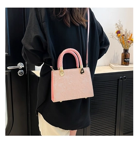Detail of pink crossbody bag with 3D floral embossing and woven top handle detail