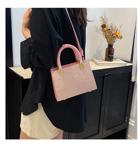 Detail of light pink crossbody bag with floral embossed texture and woven top handle
