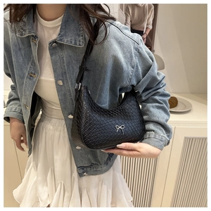 Dettaglio della borsa hobo nera intrecciata con fiocco in metallo argento e forma a mezzaluna