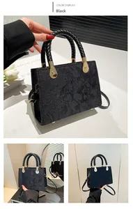 Detail of black jacquard handbag with golden hardware and woven handle texture