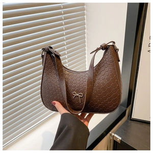 Détail de la texture tressée marron du sac demi-lune avec pendentif noeud argenté