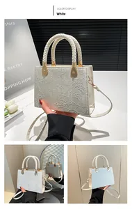 Detail of white embossed leather handbag featuring woven handle and gold hardware