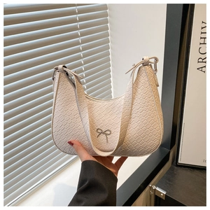 Détail du sac à bandoulière blanc cassé en similicuir croco avec nœud argenté