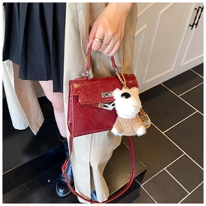 Détail du sac Kelly en cuir verni bordeaux avec un accessoire de charme ours en peluche