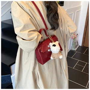 Détail du sac à main bordeaux à motif crocodile avec un pendentif chien en peluche