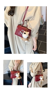 Détails du sac à main rouge foncé à motif crocodile brillant et son pendentif en peluche