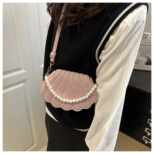 Dettaglio della borsa a conchiglia rosa con manico di perle e tracolla indossata
