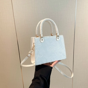 White square handbag with floral texture, top handle, and golden metal hardware details