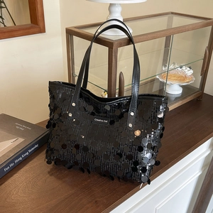 Chic black sequin tote bag with large reflective scales on a stylish vintage background