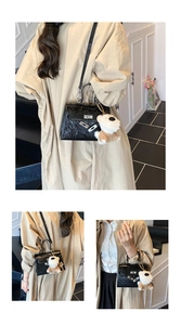 Détails d'un sac en cuir gaufré noir avec serrure en métal et breloque chien en peluche