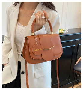 Detail of caramel leather shoulder bag featuring gold hardware and fashion tag pendant