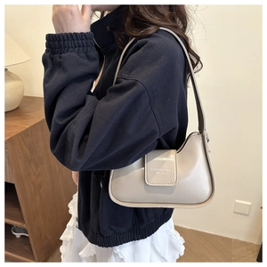 Vista lateral de un elegante bolso beige con sudadera azul marino y falda blanca
