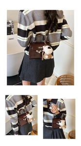 Détail du sac à main marron foncé brillant avec porte-clé peluche chien blanc