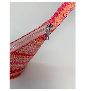 Detailed close-up of a silver metal zipper on a colorful striped woven straw beach tote bag