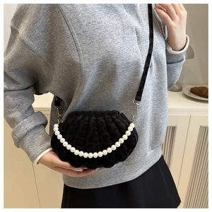 Elegante borsa a conchiglia nera con perle portata a spalla in un contesto di stile