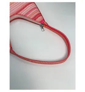 Detail of pink striped woven shoulder bag featuring premium zipper and reinforced handle