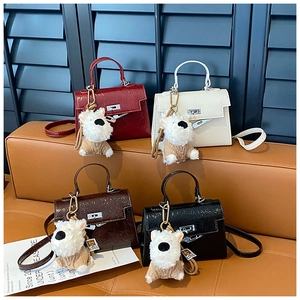 Détail de quatre mini sacs trapèze brillants en couleurs variées avec breloques en peluche