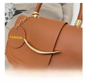 Detailaufnahme der braunen Ledertasche mit goldenen Beschlägen und runden Anhänger