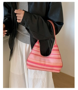 Close-up of pink and orange striped knit shoulder bag worn by a model in a leather jacket