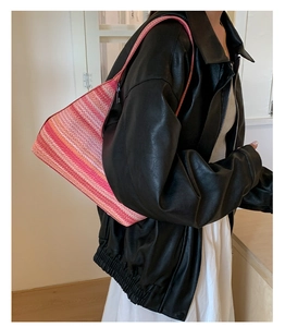 Close-up of a pink and red striped straw shoulder bag featuring a woven beach style texture