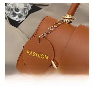Detail der braunen Ledertasche mit goldenem Bogengriff und modischem Anhänger