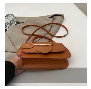 Detailaufnahme einer braunen Lederhandtasche mit goldener Metallschnalle und Anhänger