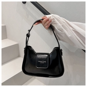 Primer plano de un elegante bolso sobaco negro sostenuto en un ambiente minimalista