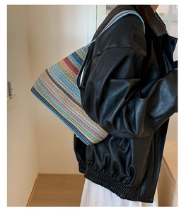 Close-up of colorful striped woven straw tote bag with thin blue leather shoulder strap